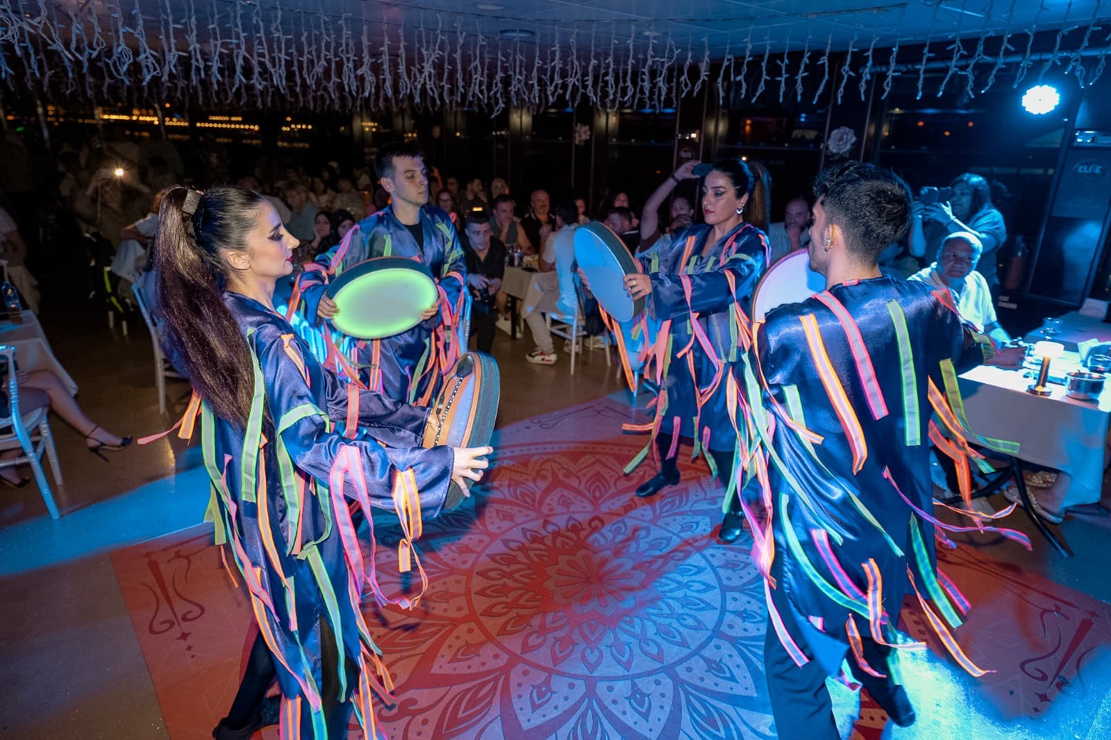 Guests seated at dinner tables on the Bosphorus cruise with stage entertainment in view