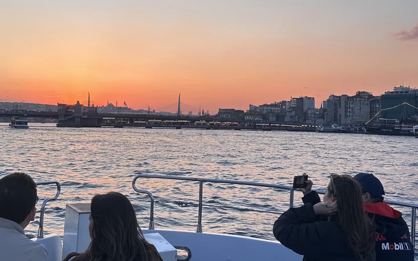 Istanbul Bosphorus cruise vessel passing Ortakoy Mosque and Bosphorus Bridge at sunset with panoramic city views