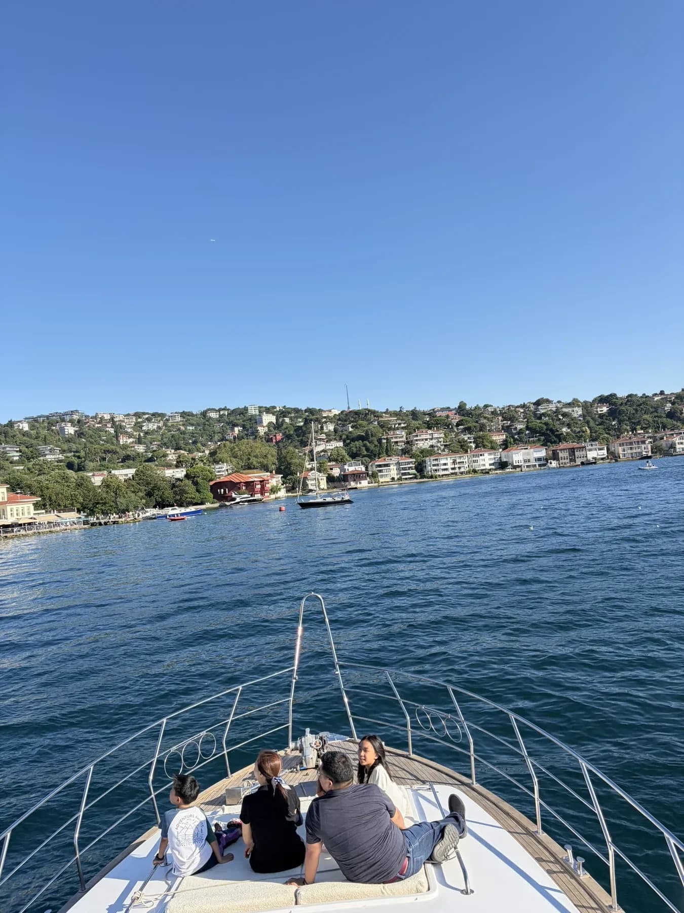 View over the bow of a yacht toward the wooded shore