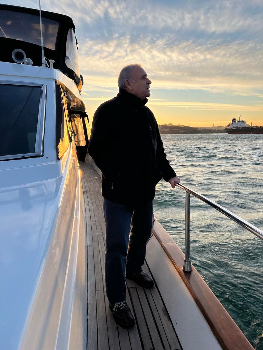 A guest in a dark coat at the rail looking across the water